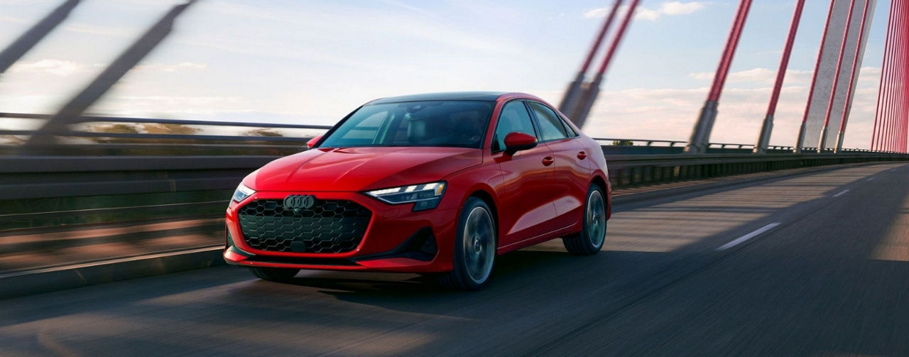 A red 2025 Audi A3 driving on a bridge after leaving an Audi dealer.